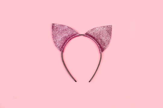 M&aacute;scara y adorno de fiesta para la cabeza en forma de orejas de gato sobre un fondo rosa pastel. Vista de frente y de cerca. Copy space