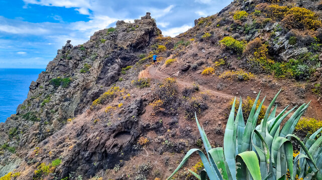 Backpack man on hiking trail from Afur to Taganana with scenic view of Atlantic Ocean coastline and Anaga mountain range, Tenerife, Canary Islands, Spain, Europe. Looking at massive rock formation