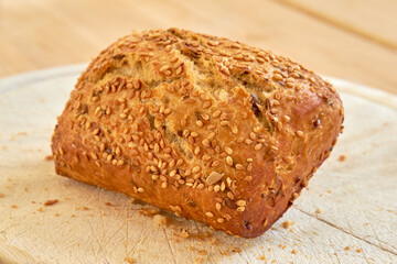 Fresh baked bread on a table at a bakery or kitchen. Homemade seeded wheat bun freshly prepared by...