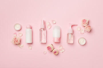 Set of small cosmetic bottles on color background, top view