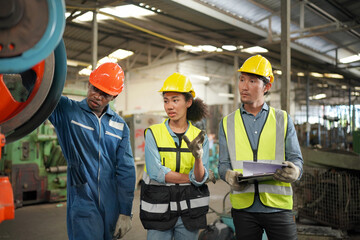 Team maintenance engineers men and women inspect relay protection system with laptop comp. They work a heavy industry manufacturing factory.