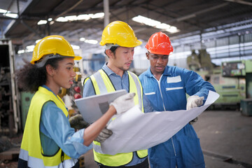 Three Heavy Industry Engineers Stand in Pipe Manufacturing Factory, Use Digital Tablet Computer, Have Discussion. Design and Construction