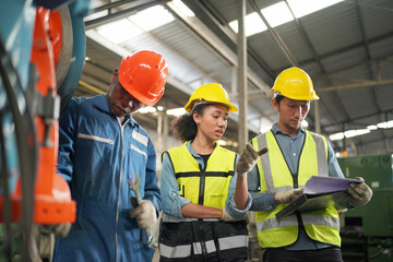 Team maintenance engineers men and women inspect relay protection system with laptop comp. They work a heavy industry manufacturing factory.
