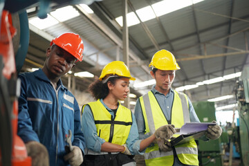 Team maintenance engineers men and women inspect relay protection system with laptop comp. They work a heavy industry manufacturing factory.