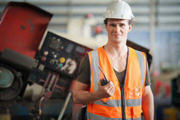 Young Caucasian hardworking heavy industry worker in protective suit and helmet using tablet and screwing valve.