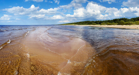 Panorama of the warm Gulf of Riga of the Baltic Sea against the background of cumulus clouds. The coast of the Gulf of Riga in Latvia is popular with tourists.