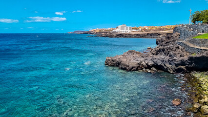 Panoramic view on a pebble stone beach Playa de San Blas near Los Abrigos, Tenerife, Canary Islands, Spain, Europe, EU. Coastline of the Atlantic Ocean. Big white vacation resort Santa Barbara