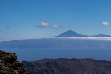 Scenic view on cloud covered volcano mountain peak Pico del Teide on Tenerife seen from Mirador Morro de Agando, La Gomera, Canary Islands, Spain, Europe. Lookout near Roque de Agando. Atlantic Ocean