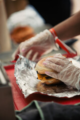 Close up view of the hands of a cook preparing a hamburger in a food truck during a music festival