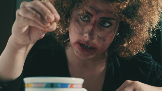 psychotic woman with dirty face crumbles a cookie into the cup of milk