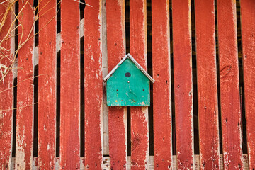 Turquoise birdhouse on faded red barnwood side