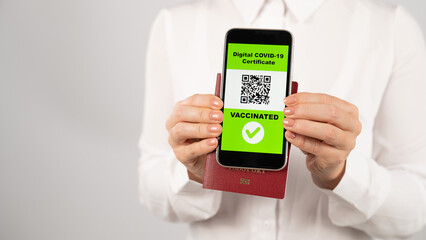 Woman holding passport and phone with qr code about vaccination.