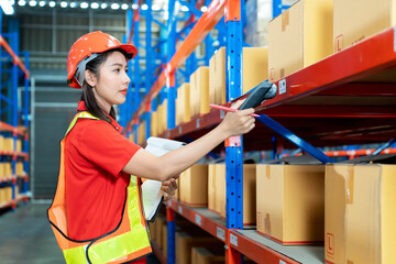 Female worker with protective vest and scanner, holds document, standing at warehouse of freight...