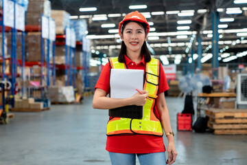 Smart smiling Asian woman working in store warehouse. She is standing and holding document folder...