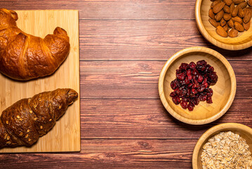 Croissants and their ingredients, products for a delicious breakfast. Top view with rustic wooden table in the background.