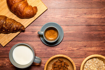 Breakfast table with a cup of espresso coffee in the center, top view with rustic wooden table in the background.