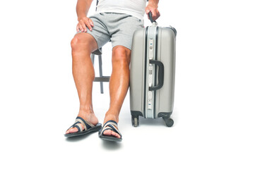 Traveler man in shorts with travel suitcase sitting in a chair on white background