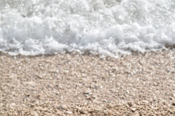 Beach shore wave close up background with copy space. Rocky beach washed with white wave.