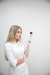 Portrait of blonde woman dermatologist with dermatoscope in white lab coat and white gloves on the...