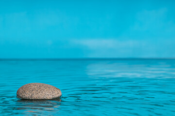 Zen-style minimalist composition. Stone in water with space for text. Blue color, copy space .