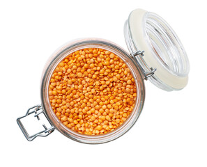 Heap of uncooked dry red lentils in glass storage jar isolated on white background top view.