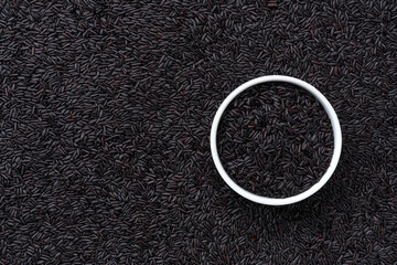 ceramic plate with black rice on a thai black rice background close-up top view.