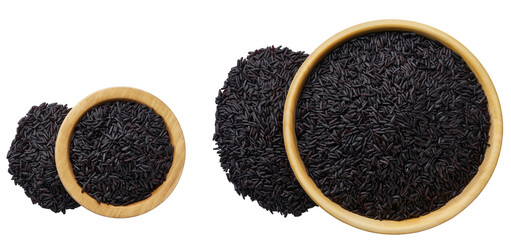 Grains black rice are scattered out of the wooden bowl top view.