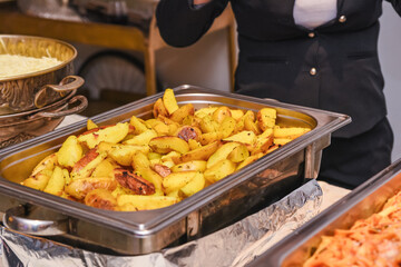a stainless steel tray on a buffet full of baked potatoes