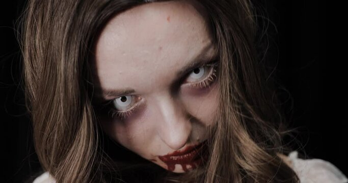 The face of an evil zombie girl is looking for her new victim. Halloween horror concept.