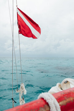 Tip of a sailboat with a red and white diving flag