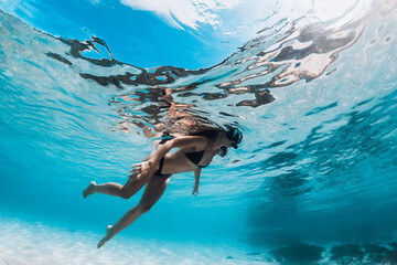 Woman with diving mask swimming underwater in transparent sea with sandy bottom
