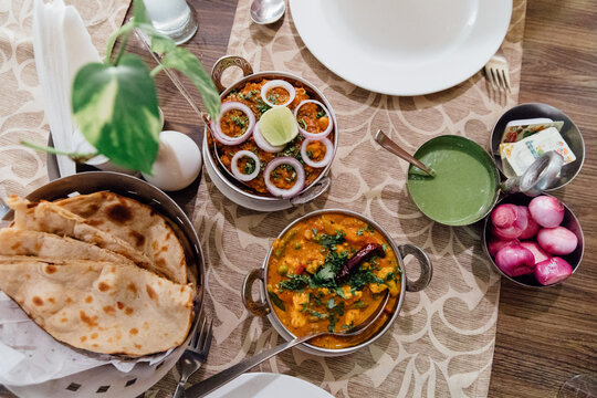 Indian lunch sits on a table, with curries and naan bread