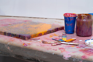 Tavolo di lavoro artistico con tela dopo un lavoro di colata acrilica. Acrylic pouring