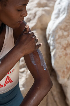 Black tourist smearing sunblock on arm