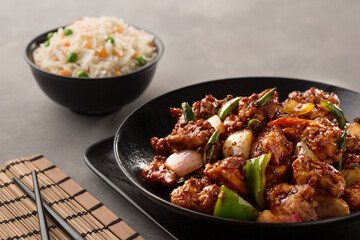 chicken chilli chinese with fried rice served in dish isolated on dark background side view