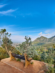 Bench with a beautiful view of Table Mountain and sea against a clear blue sky background with copy space. Relaxing spot for a peaceful break to enjoy the scenic landscape after a hike up a cliff