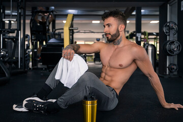 Fototapeta na wymiar Handsome male with tattoos in his 20s posing in the gym