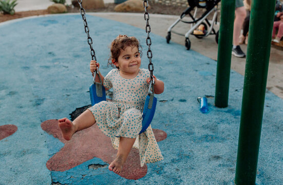 Barefoot girl wearing dress on blue swing