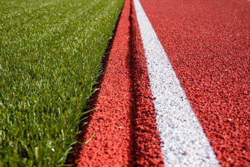 Sports stadium background. Red artificial rubber ground running tracks and white line and green...