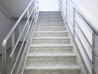 Empty stairway with chrome colored handrails at industrial prefabricated building.