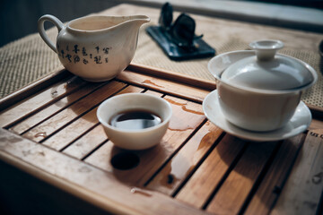 Hands of man brewing puerh tea. Man pours tea from gaiwan to bowl at tea tray. Chinese traditional gongfu cha tea ceremony.