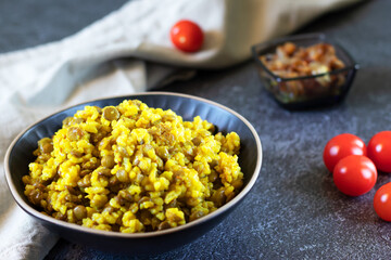 Mujadara: lentils, rice and fried onions on dark background with light textiles