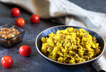 Mujadara of lentils, rice and fried onions on a dark background with tomatoes