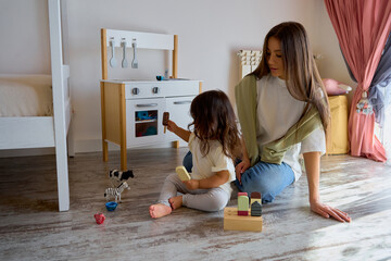 mom and daughter play with toy kitchen