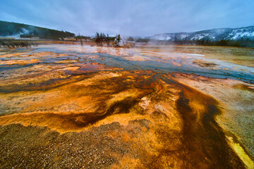 Winter at Yellowstone basin with pools of alkaline water making colorful waves