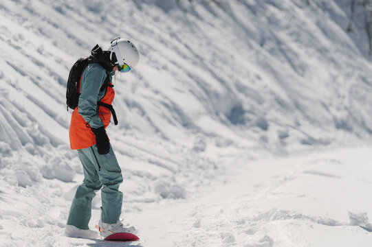 Young sporty lady practicing snowboarding in mountains