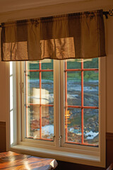 Old vintage window design wall in a home building. Background of outdoor terrain with light shining into windows. Wooden frame design with protective steel bars and ancient locks on wood frames.