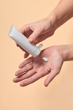 Woman squeezing cream on hand during skin care routine