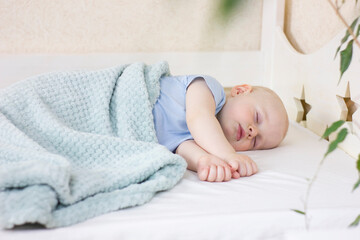 Cute sleeping baby boy in a bed.