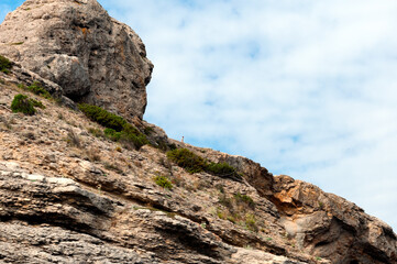 A man in the distance stands on a mountain cliff.
